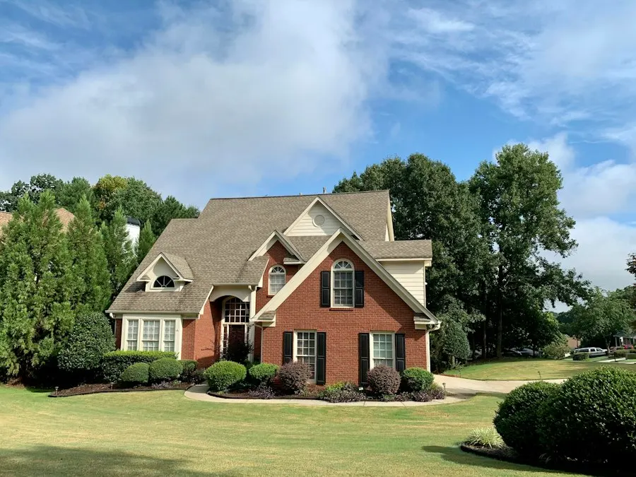 Two-story red brick house with a gabled roof, arched windows and black shutters