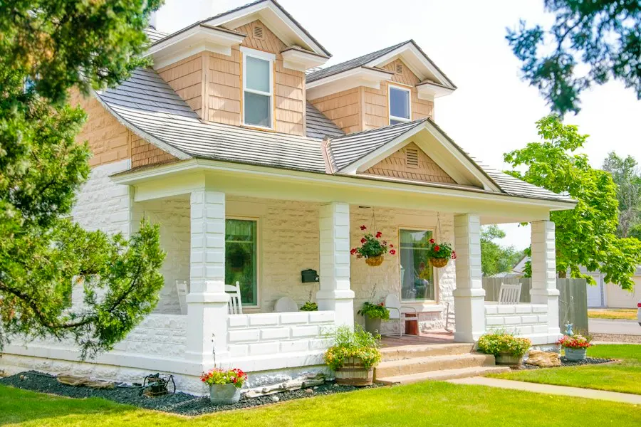 Cream-colored craftsman home with a wide covered porch, white columns and hanging flower baskets