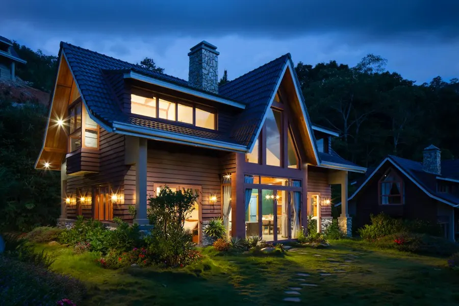 Additional sample photo: wood-clad home with steep roofs, a stone chimney and glowing windows at dusk, set among trees